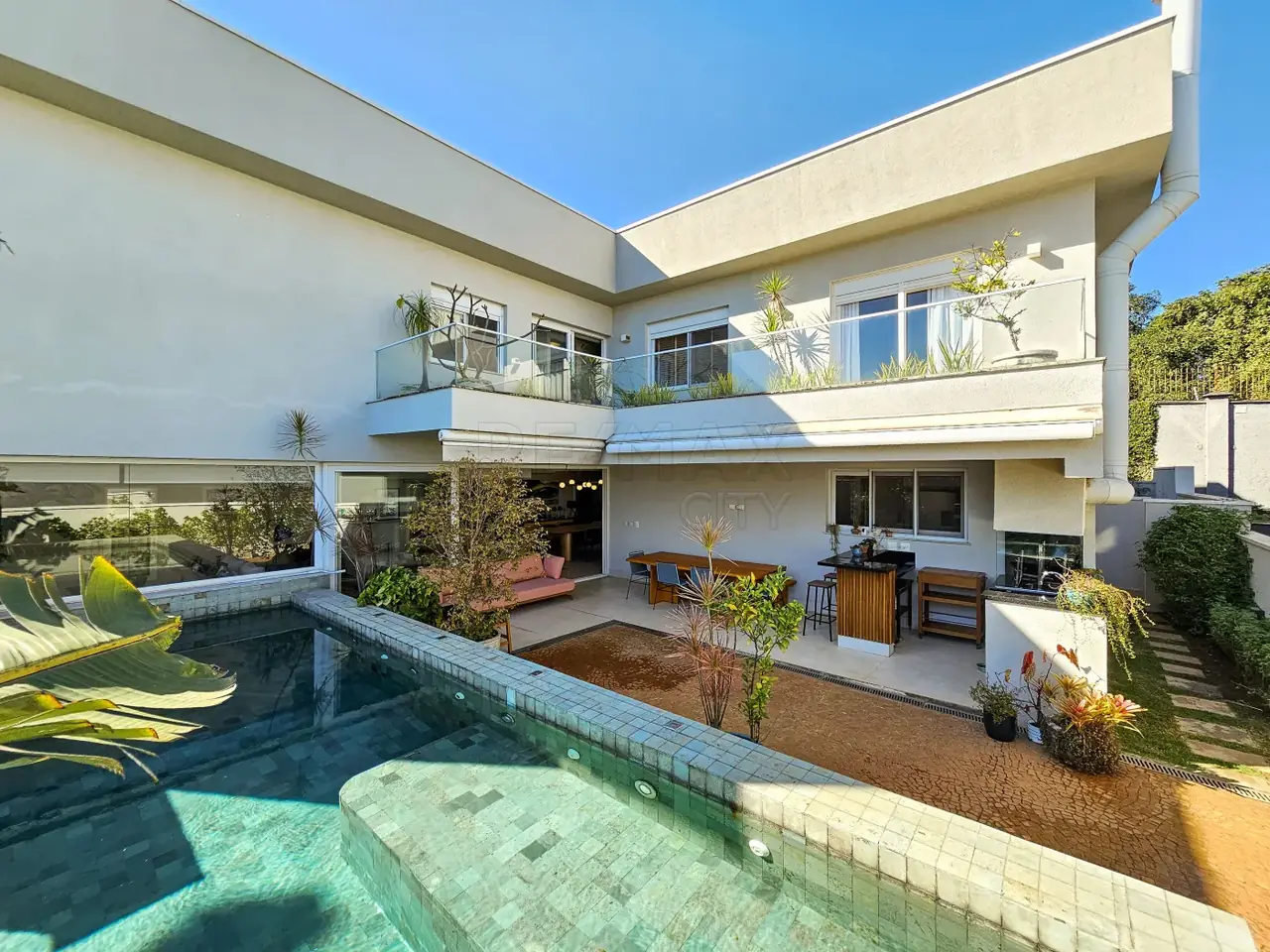 Fachada traseira da casa com piscina de borda infinita